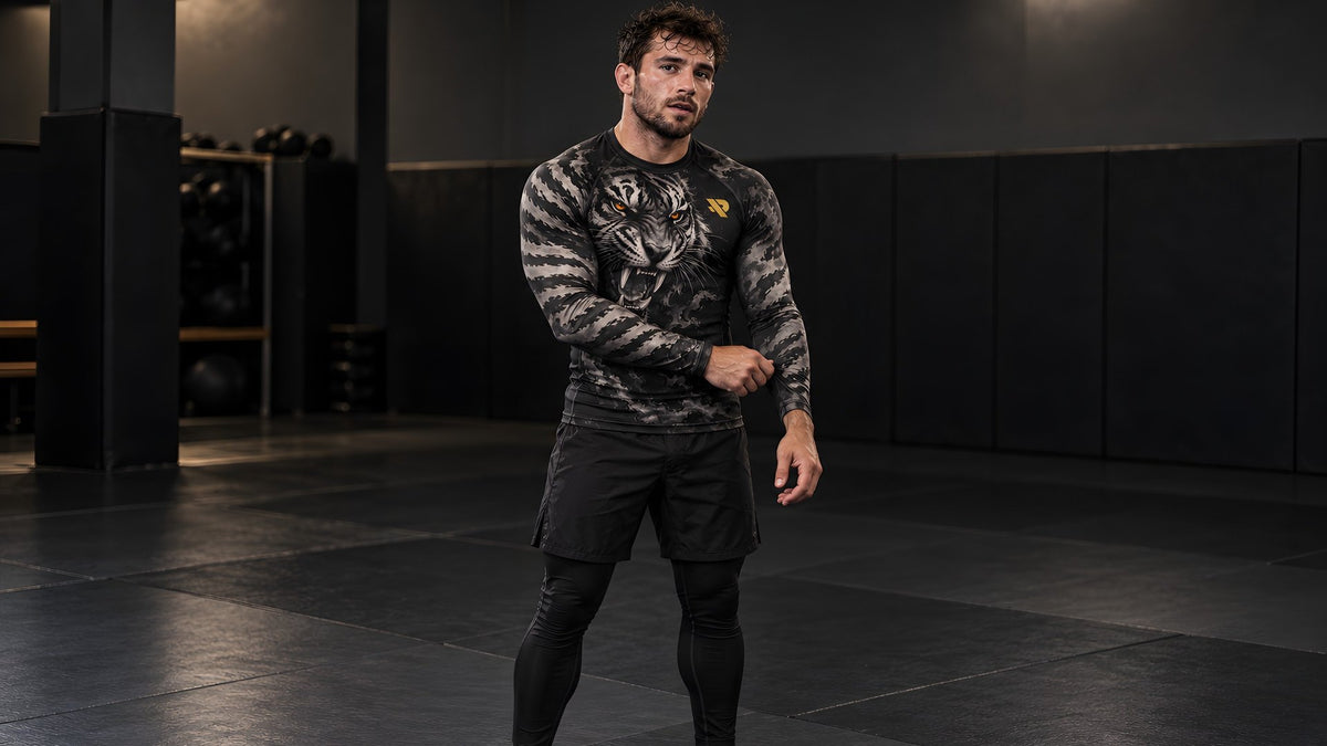 Combattant debout sur le tatami en rash guard Rashu Tigre, short et spats